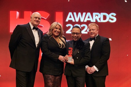 Jo Marinas, Deputy Director of Nursing Workforce Development and co-founder of Scouse School and Alexandra Spearritt, Deputy Divisional Nursing and AHP Director, and key member of the initiative’s leadership team hold their HSJ Award on stage with representatives stood either side. The pair have huge smiles on their faces and are filled with pride as they pose for pictures in front of healthcare colleagues across the UK.