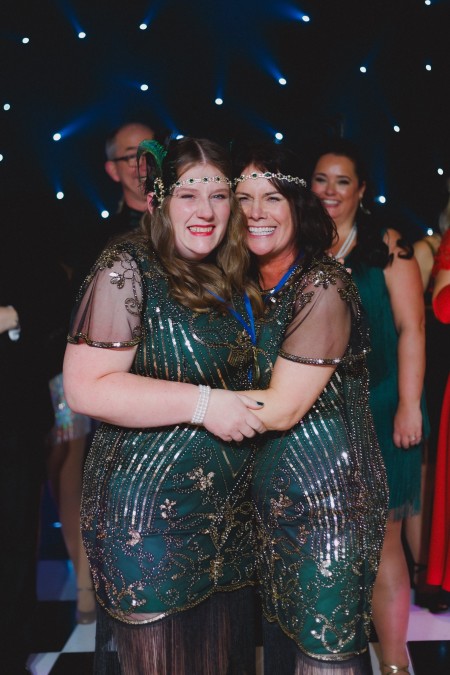 Donna and Helen hug in delight after being awarded the judges' champion. They are both dressed in flapper girl outfits and have huge smiles on their faces